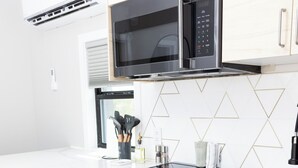 A modern kitchen with a microwave, oven, and sink. - Stardust Big Bend Container Home (Terlingua)