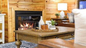 A cozy room with a fireplace, wooden walls, a television, and a coffee table with decorative items.