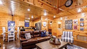 A wooden interior with a brown leather sofa, a dining table, and a kitchen area.