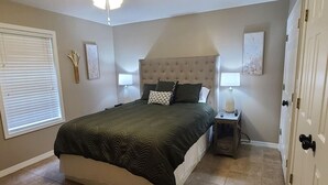 Un dormitorio con cama, lámparas de noche, mesita de noche y una puerta.