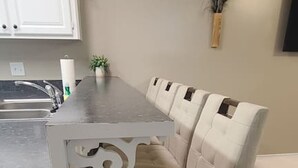 Una cocina con una isla blanca, un lavabo y un sofá beige.