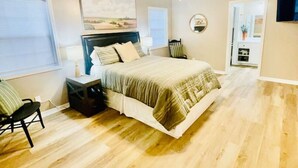 A bedroom with a bed, a chair, a nightstand, a ceiling fan, and a window.