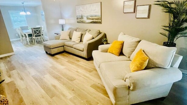 A living room with a sectional sofa, a dining area with a table and chairs, and a ceiling fan.