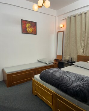 Relax in a cozy space with a single bed, nightstand, and small table for work or relaxation.