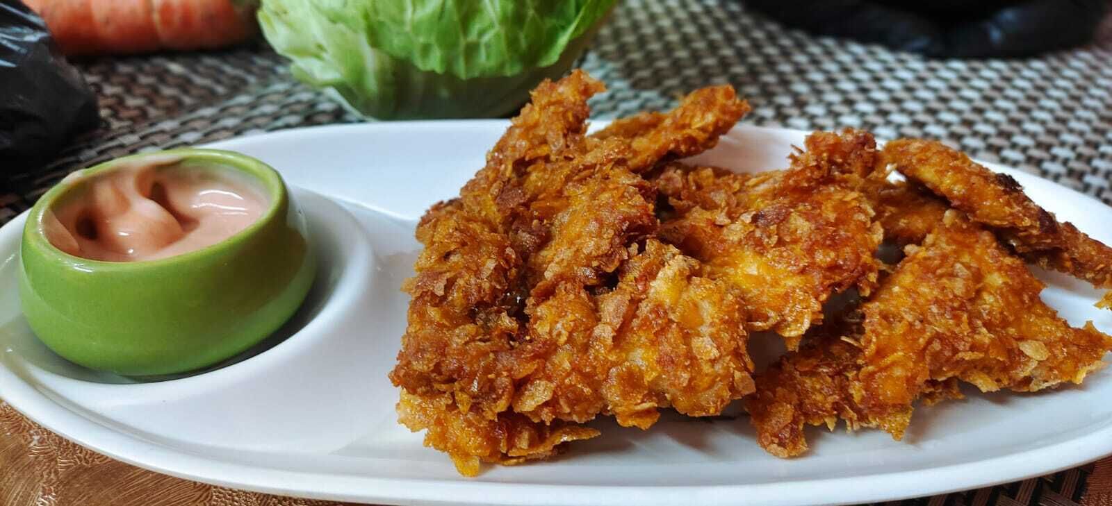 A plate of fried chicken with a side of dipping sauce.