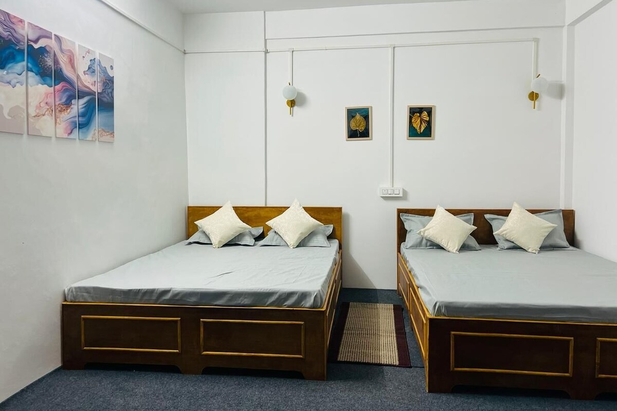 A room with two beds, white walls, and a ceiling light fixture.