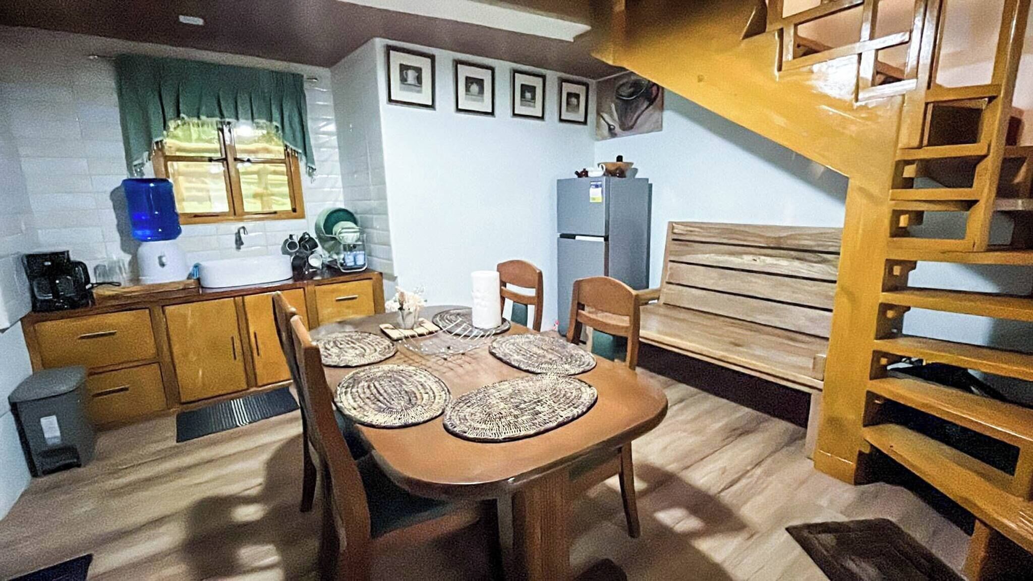 Une cuisine compacte avec des meubles en bois, un évier et un coin repas comprenant une table et des chaises en bois.