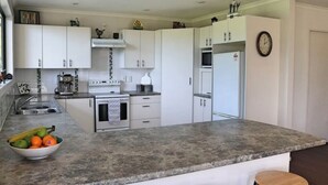 A modern kitchen with white cabinets, a granite countertop, a built-in oven, and a refrigerator. - Rose End Escape.
Home comfort in the central Wairarapa country side  (Dalefield)