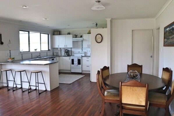 A modern kitchen with white cabinets, a central island, and a dining area with wooden chairs. - Rose End Escape.
Home comfort in the central Wairarapa country side (Dalefield)