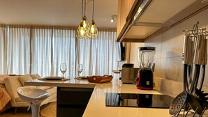Et moderne køkken med en central ø, et spiseområde med en sofa og en barstol.