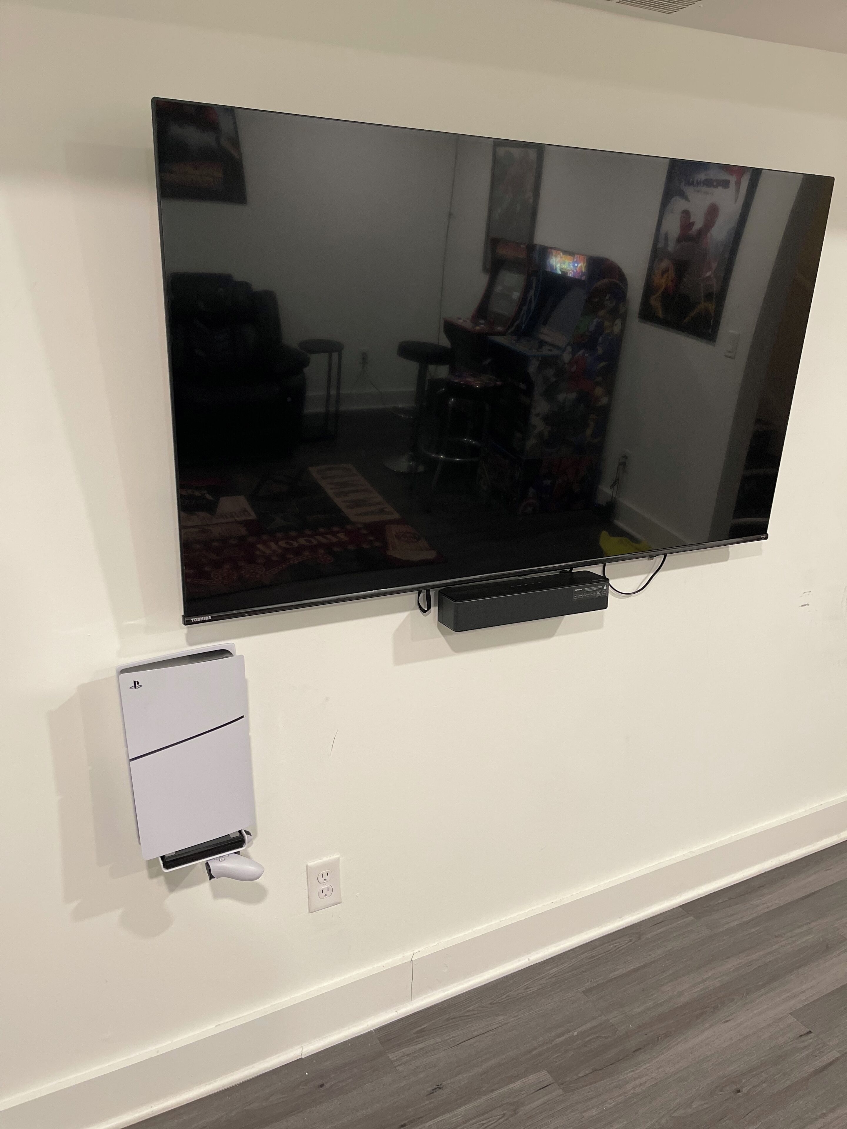 Un téléviseur à écran plat fixé à un mur blanc, avec une petite prise électrique située en dessous.
