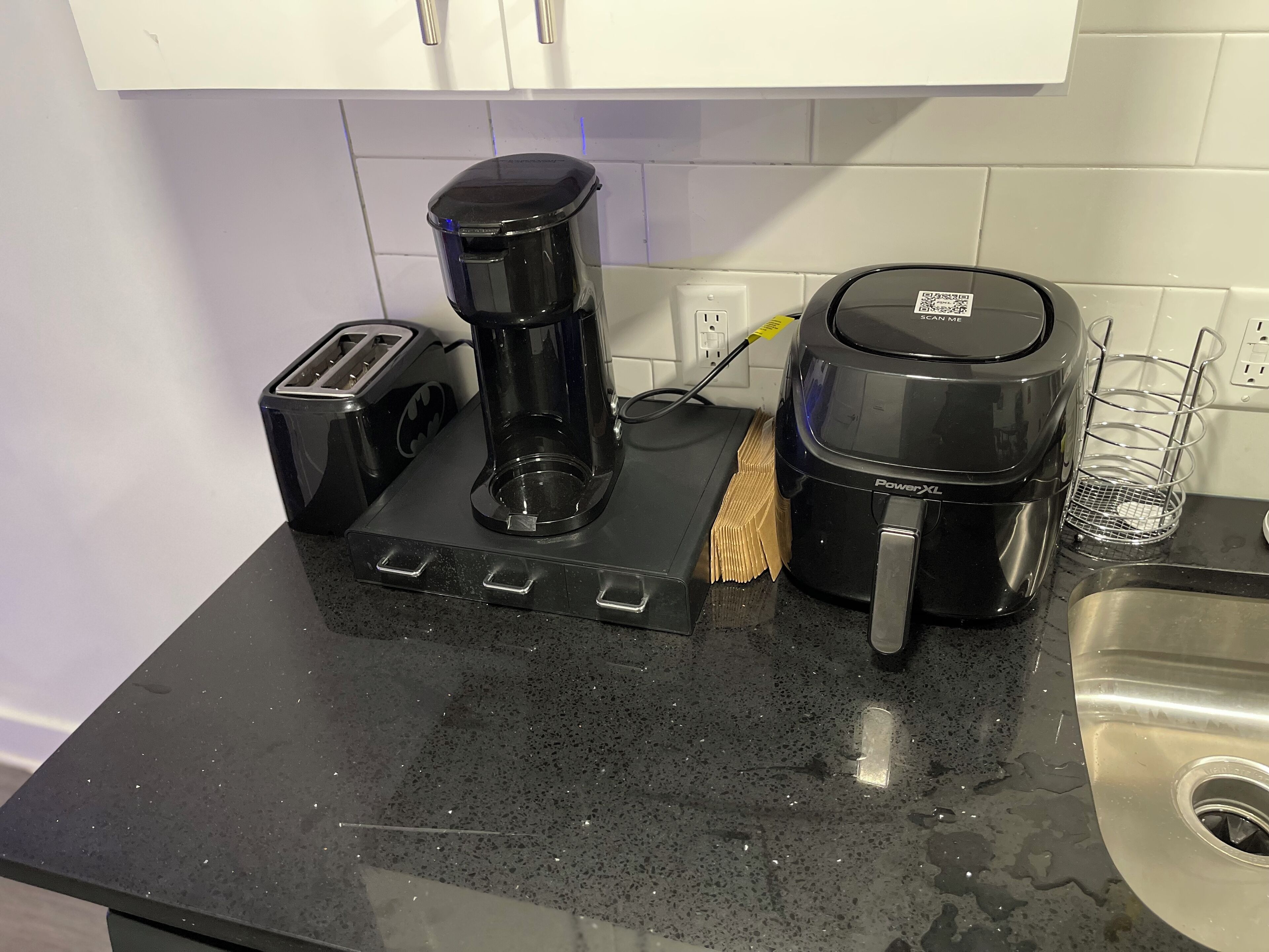 A kitchen counter with a coffee maker, toaster, and a power outlet.