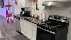 Una cocina moderna con armarios blancos, una estufa de acero inoxidable y una encimera negra.
