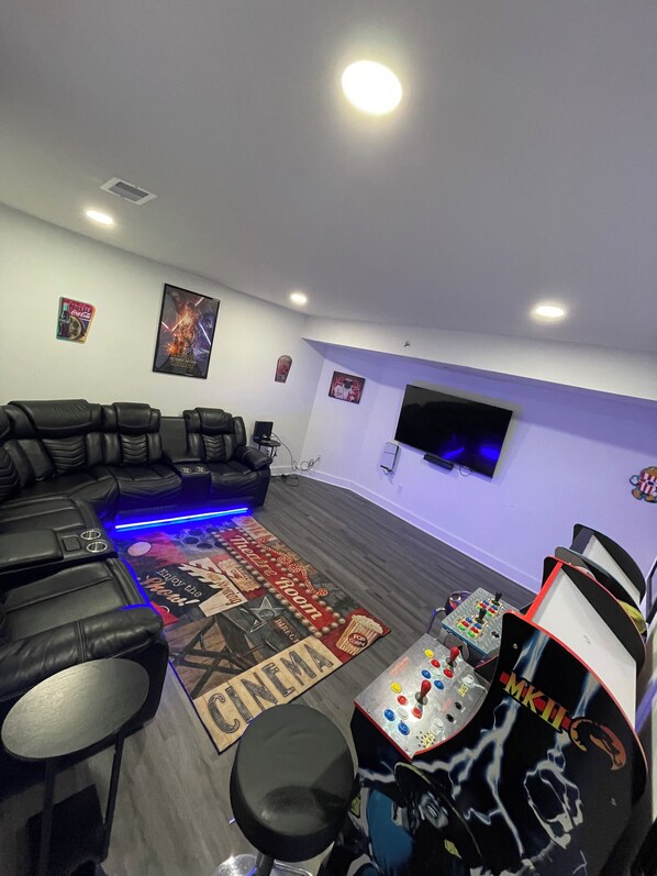 Una sala moderna con un sofá modular, una mesa de juegos y un televisor de pantalla plana montado en la pared.