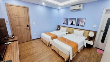 Habitación de hotel con dos camas, un armario de madera, un escritorio con teléfono y aire acondicionado instalado en la pared.