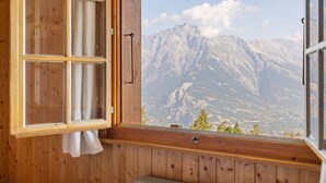 A wooden cabin with a large window overlooking a mountain range.