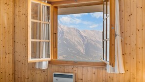 A wooden room with a large window, a bed, and a heater.