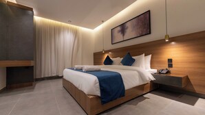 A modern hotel bedroom with a wooden bed, a bedside table with a phone, and a large painting on the wall. - Arjaan Park Al Shifa (Riyadh)