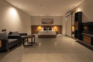 Un dormitorio moderno con una cama grande, un sofá, una mesita de centro y un televisor.