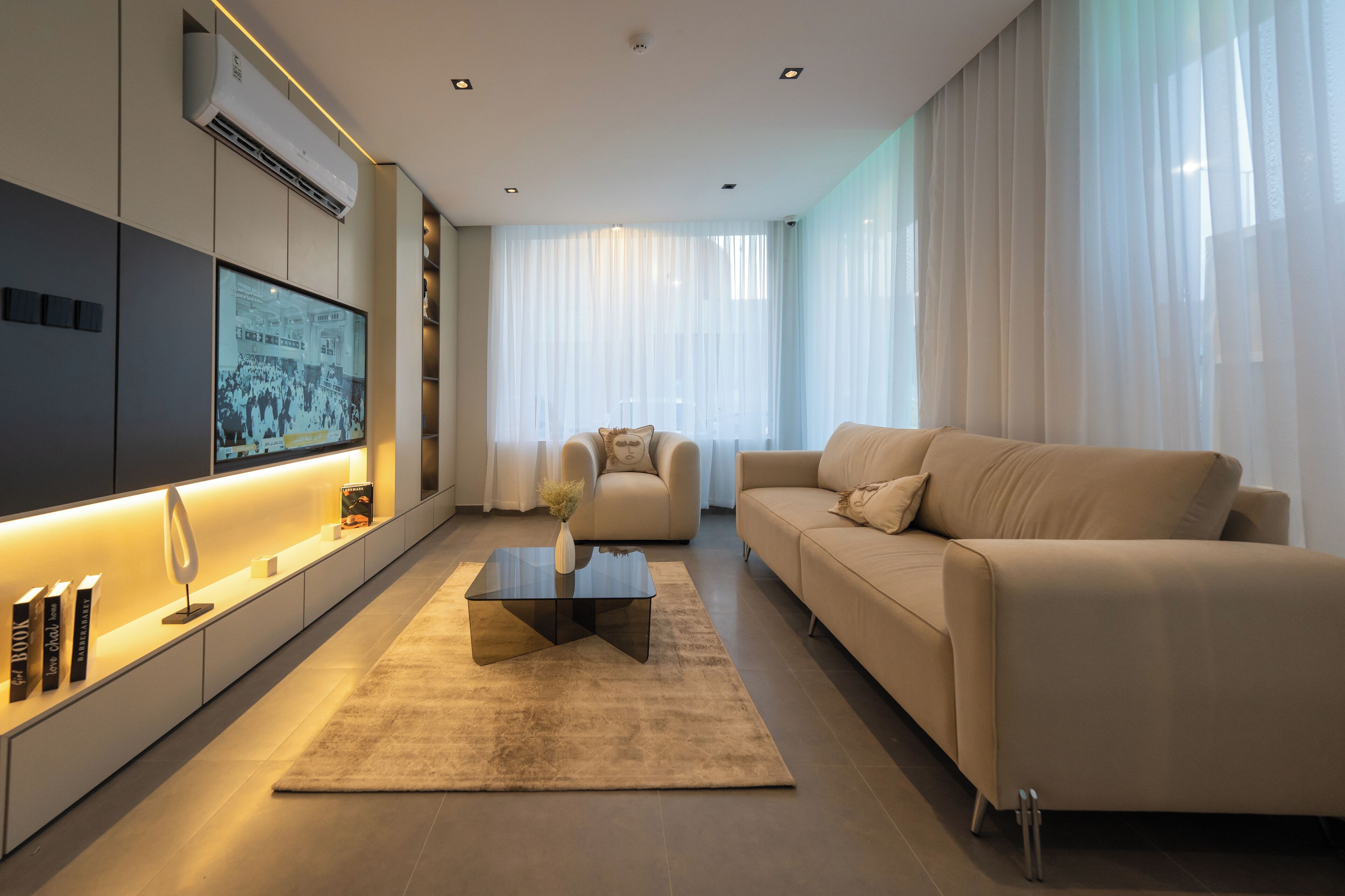 Een moderne woonkamer met een flatscreen televisie, een bank, een salontafel en een boekenkast.