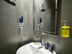 Un baño moderno con un lavamanos blanco, accesorios de cromo y un espejo encima.