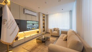A modern living room with a sofa, a coffee table, and a TV. - Arjaan Park Al Shifa (Riyadh)
