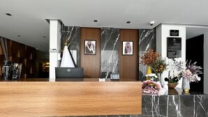 A reception desk with a marble countertop, framed photographs on the wall, and floral arrangements. - Arjaan Park Al Shifa (Riyadh)