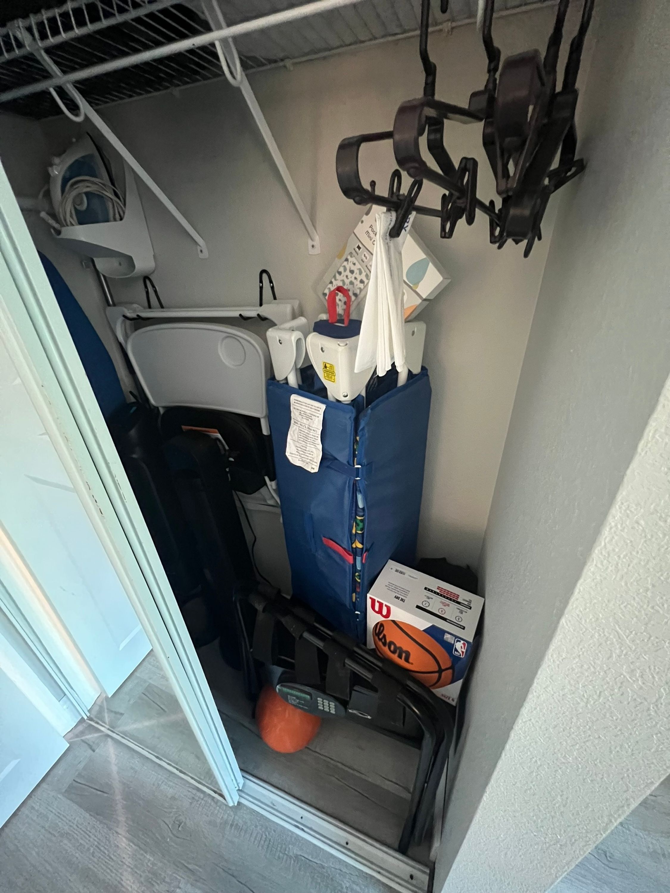 A compact storage area with a blue storage bin, a white plastic bag, a black electronic device, and a basketball box.