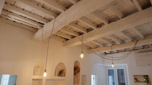 Een kamer met zichtbare houten balken, een flatscreen televisie en hanglampen.