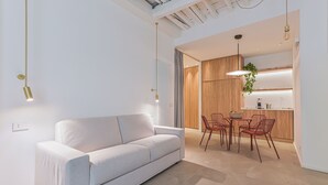 Een moderne woonkamer met een bank, eettafel, stoelen en hanglampen.
