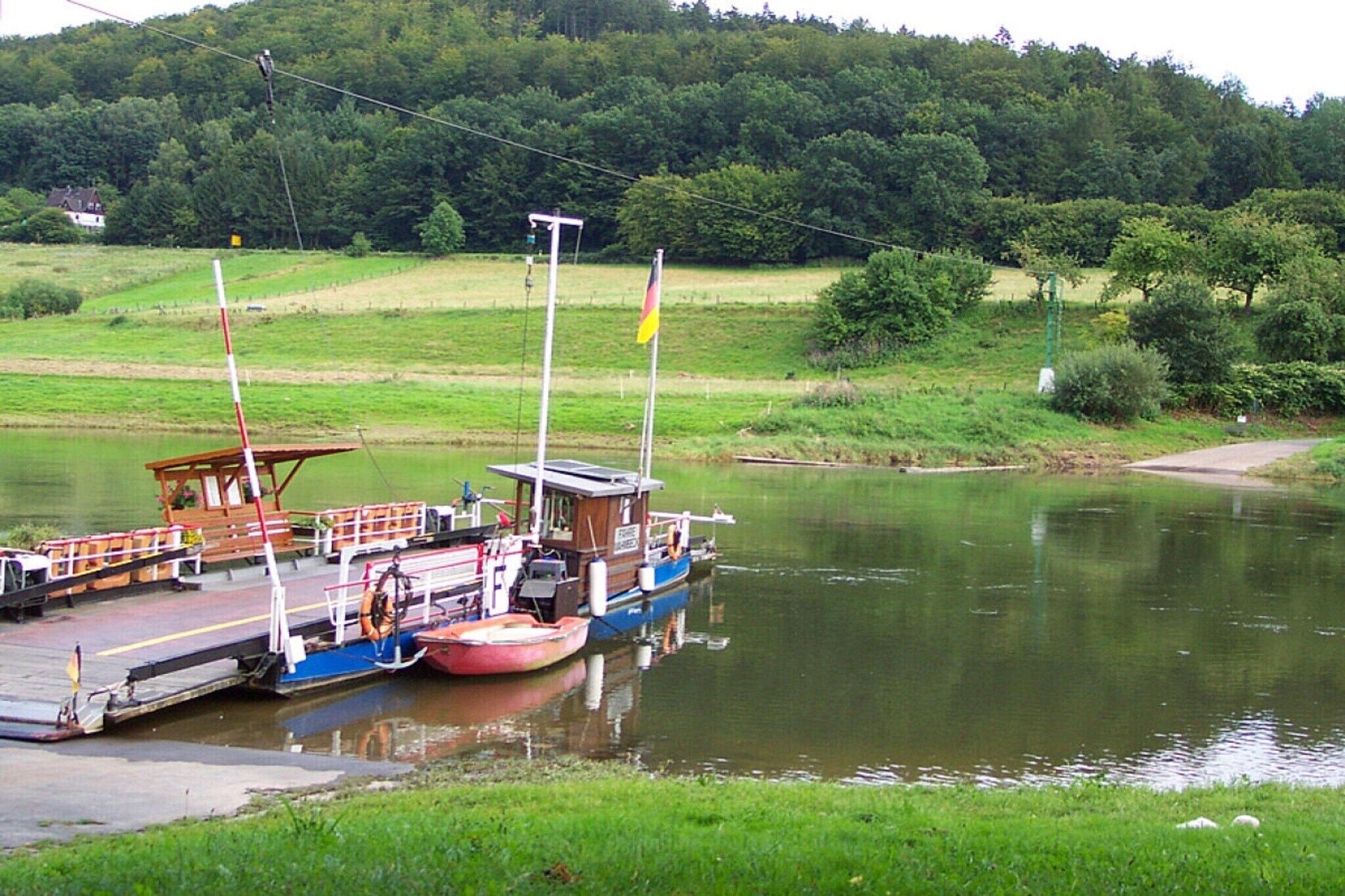 Un bateau fluvial était amarré sur une rivière paisible, avec une colline boisée en arrière-plan.