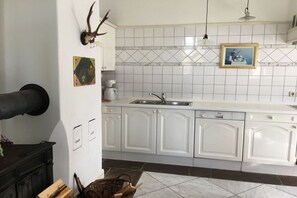 Cuina amb armaris blancs, una rentavaixelles, una cafetera i un escorçó decoratiu penjat a la paret.