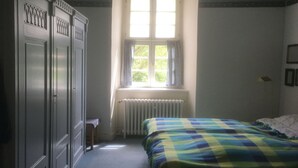 Ein Schlafzimmer mit Bett, Fenster, Heizkörper und Kleiderschrank.