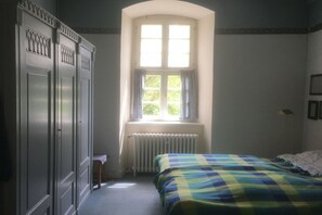 Ein Schlafzimmer mit Bett, Fenster, Heizkörper und Kleiderschrank.