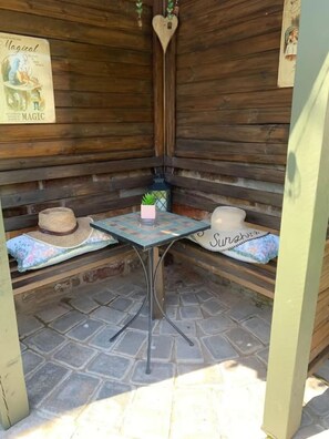 A wooden booth with a table and benches, decorated with a heart-shaped ornament and a poster.