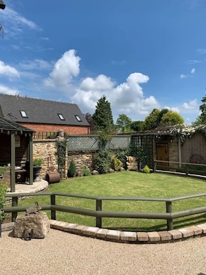 A rustic barn with a stone wall, a wooden fence, and a gravel path. - The Old Horns cottage (Higham)