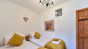 Ein Zimmer mit zwei Betten, einem Chandelier, einem herzförmigen Dekor, einem gerahmten Bild und einer Holztür.