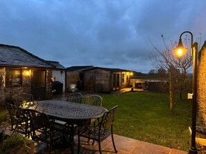 A patio area with a round table and chairs, a stone pathway, and a small lawn.