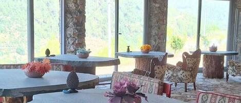 An outdoor seating area with stone tables and benches, surrounded by large windows offering views of the landscape.