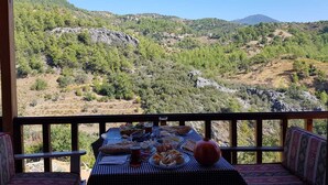 A table set with food and drinks on a balcony with a mountain view. - Hergül Holiday Village (Gazipasa)