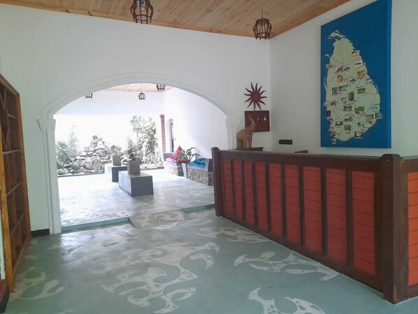 An interior hallway with a wooden ceiling, a red bench, a map on the wall, and a view of the outside.