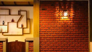 A room with a wooden floor, a brick wall, and a shelf with bottles. - NATURALIZA (Dambulla)