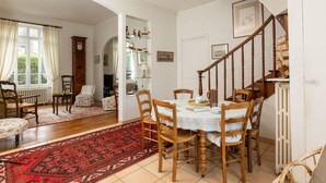 Ein Essbereich mit einem Holztisch und Stühlen, einem roten Teppich mit Muster und einer Treppe, die zu einer oberen Ebene führt.