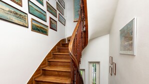 Eine Holztreppe mit Geländer, umgeben von gerahmten Bildern an den Wänden.