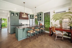 Cozinha moderna com ilha central, banquetas e mesa de jantar com cadeiras.