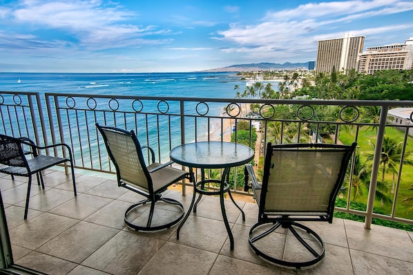 Un balcon avec vue sur l’océan, une table ronde et deux chaises.