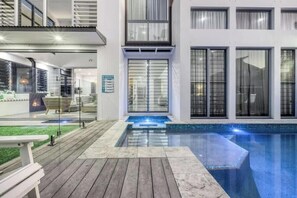 A modern building with a swimming pool, large windows, and a deck area. - Frangipani Beach House (Kingscliff)