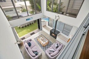 A modern living room with a fireplace, a dining area with a view of the garden, and a balcony with a view of the neighborhood.