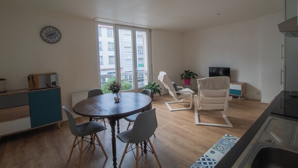 A modern living space with a dining area, a TV, and a kitchen.