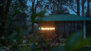A modern building with a neon sign reading "Tentgram" in the evening. - Tentgram Plantation Hostel Suryanelli  (Devikolam)